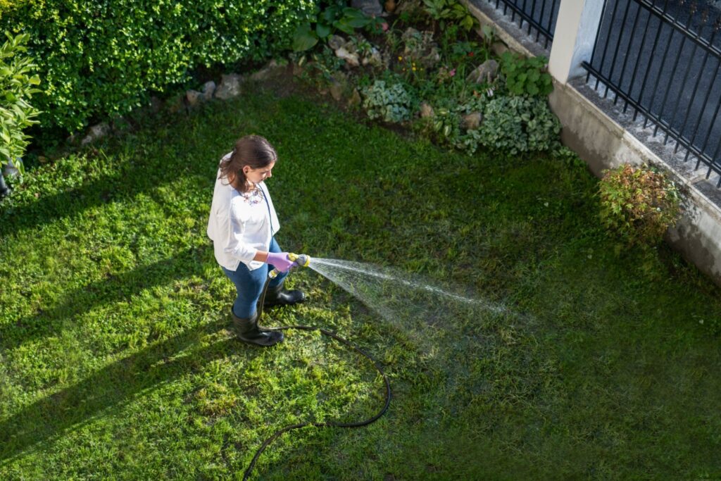 happy woman watering garden with water hose